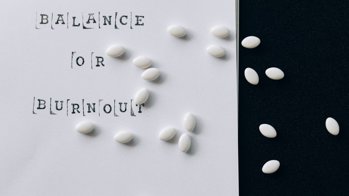 Conceptual image featuring 'Balance or Burnout' text with scattered white capsules.